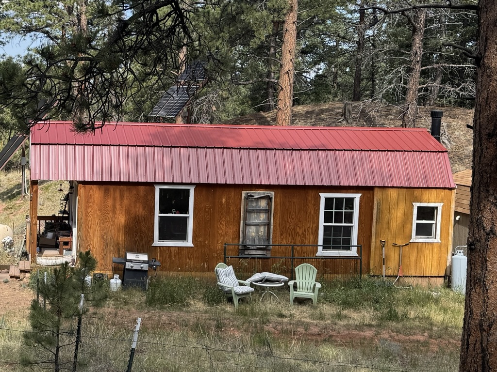 Wood-sided lofted cabin with a red metal roof among pine trees in Colorado