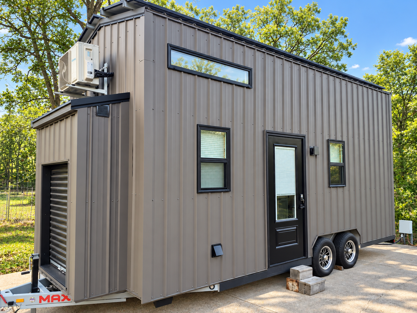 Gray metal-sided tiny house on a dual-axle trailer with a mini-split unit mounted high on one end